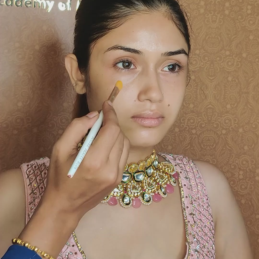 artist using concealer brush on model under eyes