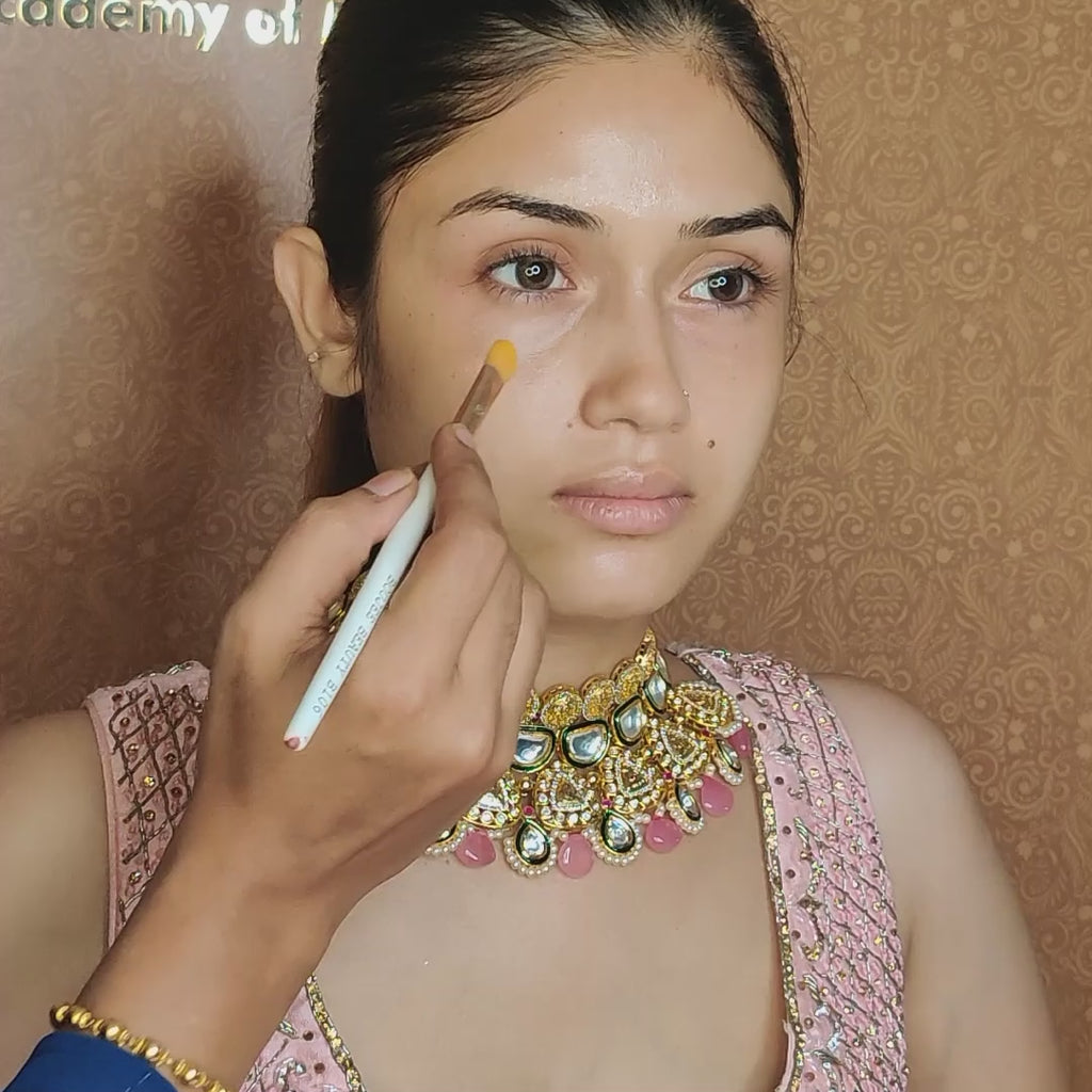 artist using concealer brush on model under eyes 