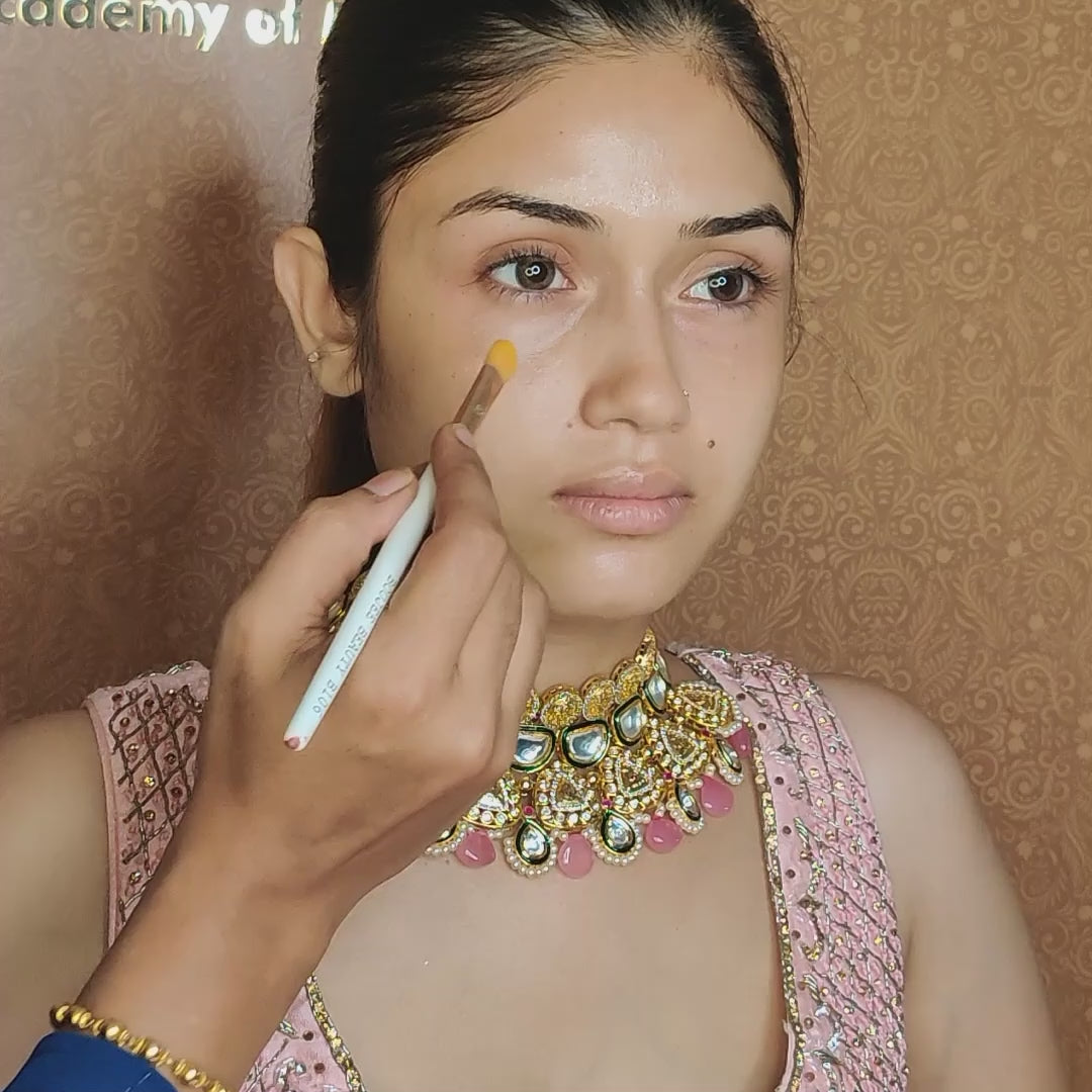 artist using concealer brush on model under eyes 