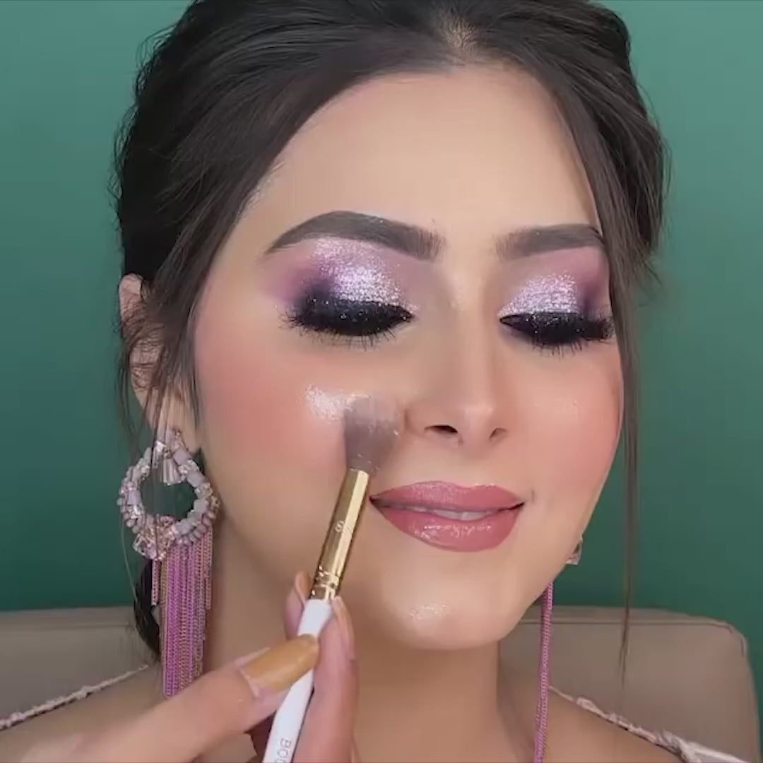 artist using fluffy highlighter brush on model cheeks